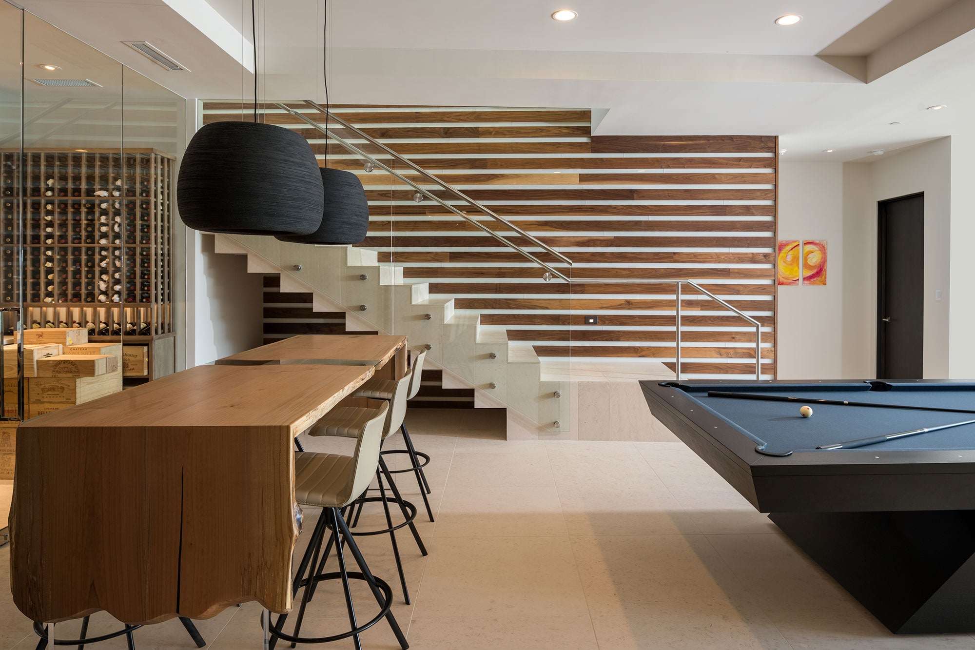 Modern interior with a pool table, dining area, and staircase.