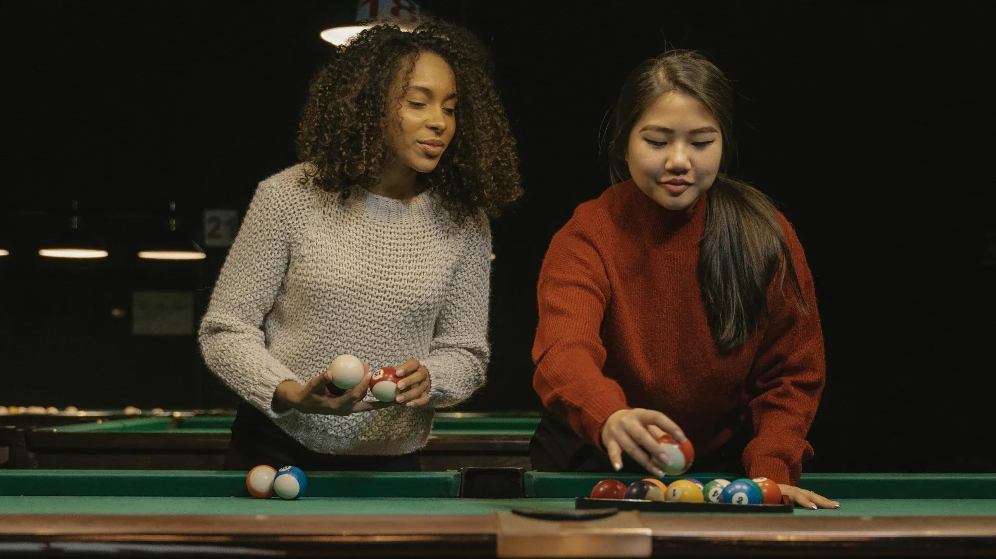 Two women setting up a game of billiards